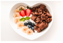 A heart shaped plate with fruits and oats with milk or joghurt.
