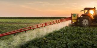 An image of a tractor spraying pesticides in a field.
